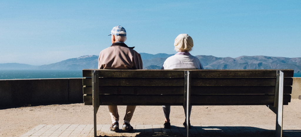 elderly couple sitting on bench outside